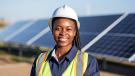 A black woman engineer standing in front of a row of solar panels